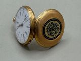 une montre de poche en or posée sur une surface blanche
