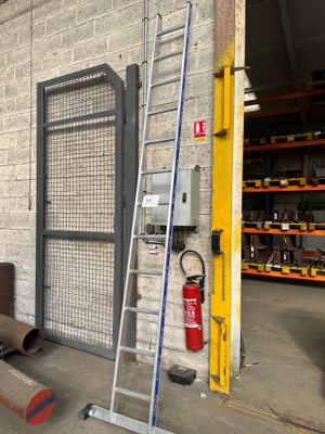 une échelle appuyée contre un mur, à côté d'une borne d'incendie
