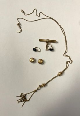 un ensemble composé d'un collier et de boucles d'oreilles en or, posé sur une surface blanche