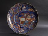 une assiette bleue décorée, posée sur un support