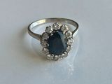 une image représentant une bague ornée d'une pierre bleue entourée de diamants blancs