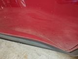 a close up of a red car with a denting on it