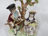 a figurine of a man and a woman sitting under a tree