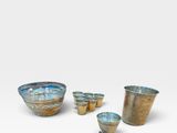 a group of four bowls and cups sitting on top of a white surface