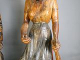 une statue en bois représentant une femme tenant une batte de baseball