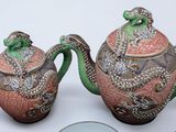 a tea pot and a tea pot with a dragon on it next to a plate