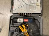 a tool in a case on the floor next to a pair of shoes