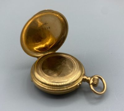 une image d'une montre de poche en or sur une surface blanche