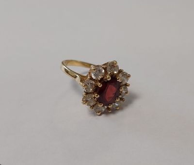 un gros plan d'une bague ornée d'une pierre rouge entourée de petites pierres blanches