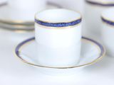 a white cup and saucer with blue trim on a white table