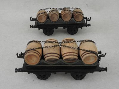 two miniature wooden barrels on a cart on a white surface