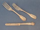 three forks and a knife on a table with a blue background