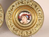 two gold plate with a picture of a woman in a red hat and a lady in a pink hat