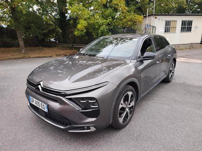 une voiture grise garée sur le bord de la route, devant une maison