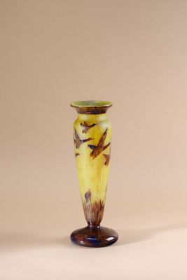 yellow and brown vase with birds on it sitting on a white surface
