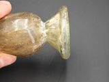 a hand holding a glass vase on a black surface