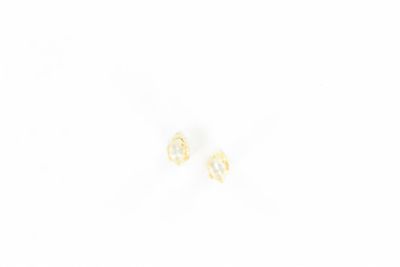 deux petites boucles d'oreilles en or ornées d'un diamant, posées sur une surface blanche