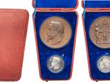 three silver and gold medals in velvet cases on a white background