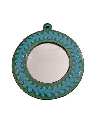 a blue and green circular mirror with a flower design