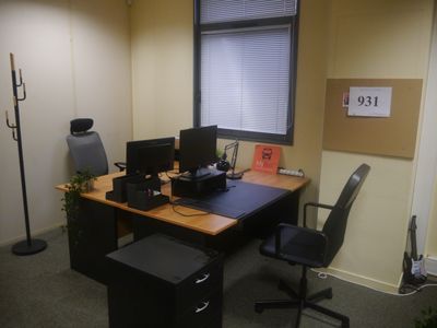 a desk with two computers and a chair in the corner