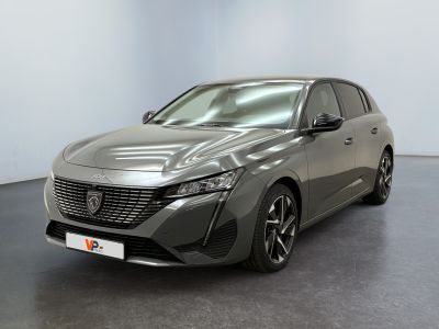 La voiture grise est garée dans une grande pièce au sol noir.