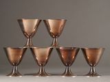 six copper goblets are lined up in a pyramid on a white surface