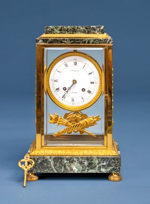 une horloge en or et en marbre sur laquelle est représenté un oiseau