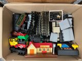 a cardboard box filled with toy trains and other toys