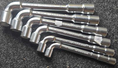 six serres-tubes en acier inoxydable sont alignées sur une surface noire
