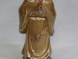 figurine of a woman in a golden robe with a red ribbon
