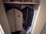 une armoire remplie de vêtements et de bagages dans un coin de la pièce
