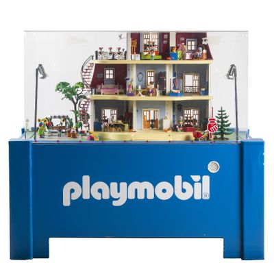une vitrine Playmobil sur laquelle est posée une maison de poupées