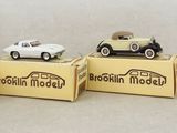 three small toy cars sitting on top of boxes on a white surface