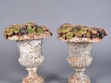 pair of stone urns with plants on top of them on a gray surface