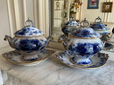 a blue and white teapot and saucer on a marble table