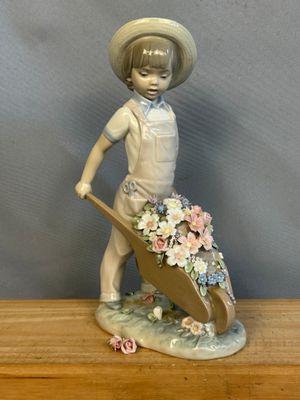 une figurine représentant un garçon avec une brouette et des fleurs