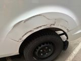 a white van with a flat tire parked in a parking lot