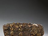 une image représentant une pierre portant une inscription, posée sur un socle en bois