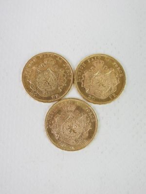 trois pièces d'or posées l'une à côté de l'autre sur une surface blanche