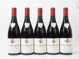 six bouteilles de vin rouge sont alignées sur une surface blanche