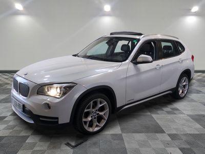 the bmw x1 is parked in a large room with a checkered floor