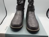 une paire de bottes noires pour femme posée sur une boîte, sur une surface blanche