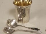 a silver cup with spoons and a spoon on a table
