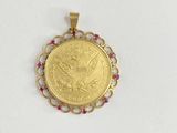 a gold coin pendant with a ruby stone in the center