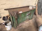 a green chest sitting in a garage next to a trash can