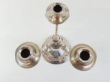 three silver candlesticks sitting on a white table