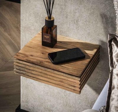 un téléphone portable posé sur une étagère en bois, à côté d'un vase contenant des roseaux
