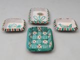four pieces of pottery with designs on them sitting on a table