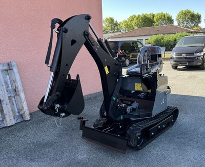 the back end of a small excavator parked in front of a building
