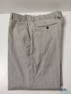 un gros plan sur un pantalon gris posé sur une surface blanche